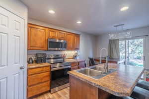 Kitchen featuring sink, stainless steel appliances, pendant lighting, a breakfast bar area, and a kitchen island with sink