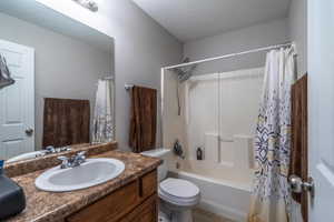 Full bathroom featuring shower / bathtub combination with curtain, tile patterned flooring, a textured ceiling, toilet, and vanity