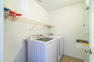 Laundry room featuring light tile patterned floors and washing machine and dryer