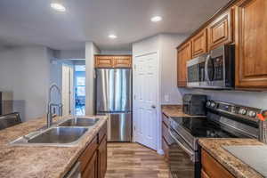 Kitchen with sink, light hardwood / wood-style flooring, and appliances with stainless steel finishes