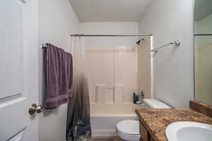 Full bathroom featuring vanity, shower / bath combo, a textured ceiling, and toilet