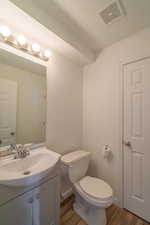 Bathroom featuring hardwood / wood-style flooring, vanity, toilet, and a textured ceiling