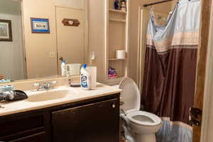 Bathroom with vanity, curtained shower, and toilet