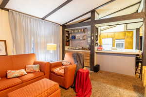 Carpeted living room featuring a textured ceiling, built in shelves, wooden walls, and lofted ceiling