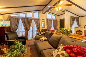 Living room with carpet flooring, lofted ceiling with beams, ceiling fan, and a textured ceiling