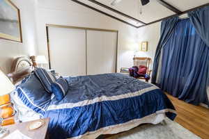 Bedroom with a textured ceiling, ceiling fan, wood-type flooring, a closet, and lofted ceiling