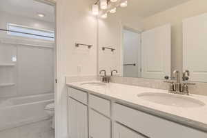 Full bathroom with tile flooring, vanity, toilet, and shower / washtub combination