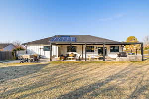 Rear view of property with an outdoor kitchen, ceiling fan, a patio, a hot tub, and a lawn