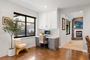 Home office featuring dark hardwood / wood-style floors, a multi sided fireplace, built in desk, and vaulted ceiling