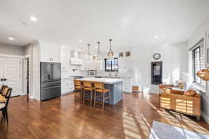 Kitchen with a kitchen bar, white cabinetry, high end fridge, and a center island