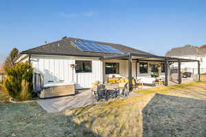 Back of property featuring outdoor lounge area, ceiling fan, an outdoor kitchen, solar panels, and a hot tub