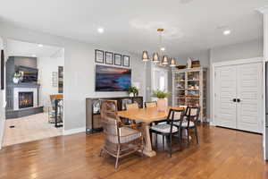 Dining space with hardwood / wood-style floors, a large fireplace, and vaulted ceiling