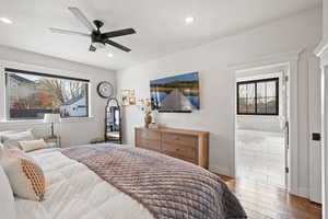 Bedroom featuring multiple windows, hardwood / wood-style flooring, ceiling fan, and ensuite bathroom