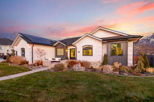 View of front facade with solar panels and a lawn