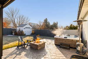 View of patio featuring a shed, a hot tub, and an outdoor fire pit