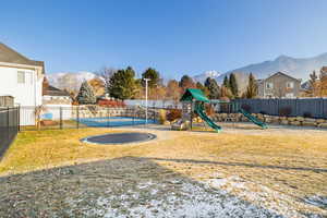 View of playground with a fenced in pool, a mountain view, a yard, and a trampoline