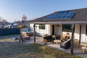 Back of house with solar panels, a patio, an outdoor living space with a fire pit, and ceiling fan