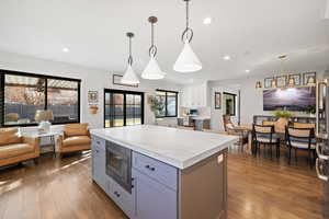 Kitchen with dark wood-type flooring, stainless steel microwave, and pendant lighting