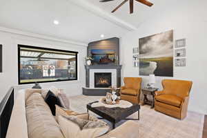 Living room with ceiling fan, a large fireplace, and lofted ceiling with beams