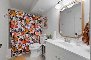 Full bathroom with a textured ceiling, vanity, toilet, and shower / bathtub combination with curtain