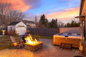 Patio terrace at dusk featuring a fire pit, a storage shed, and a hot tub