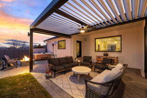 Patio terrace at dusk featuring ceiling fan, an outdoor living space with a fire pit, and a hot tub