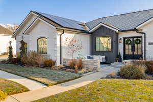 View of front facade with french doors, a front yard, and solar panels