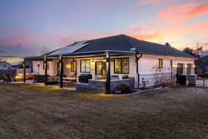 Back house at dusk featuring outdoor lounge area, a yard, and a patio