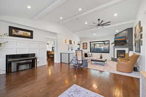 Living room featuring lofted ceiling with beams, ceiling fan, and dark wood-type flooring