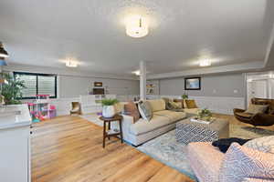 Living room featuring sink, light wood-type flooring, and a textured ceiling