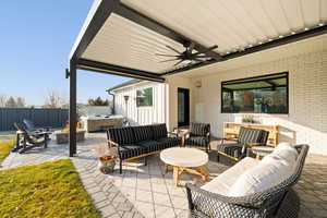 View of patio / terrace featuring a hot tub, ceiling fan, and an outdoor living space with a fire pit