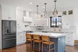 Kitchen with white cabinets, appliances with stainless steel finishes, a center island, and dark hardwood / wood-style floors