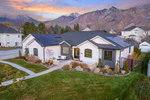 Single story home featuring a mountain view, solar panels, and a lawn