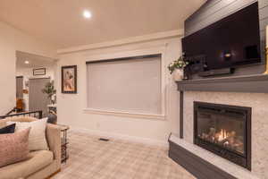 Carpeted living room with a tiled fireplace and vaulted ceiling