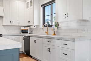 Kitchen featuring backsplash, dark hardwood / wood-style flooring, sink, and white cabinets