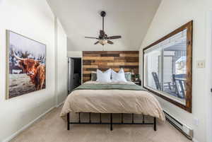 Bedroom featuring ceiling fan, lofted ceiling, baseboard heating, and light carpet