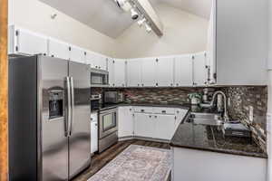 Kitchen featuring decorative backsplash, sink, white cabinetry, and stainless steel appliances