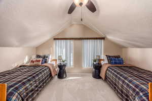 Bedroom with ceiling fan, carpet floors, a textured ceiling, and vaulted ceiling