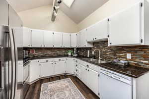 Kitchen with white dishwasher, white cabinets, sink, dark hardwood / wood-style flooring, and stainless steel refrigerator