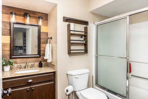 Bathroom featuring vanity, toilet, and a shower with door