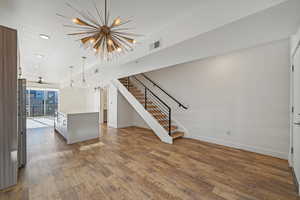 Unfurnished living room with hardwood / wood-style floors and ceiling fan with notable chandelier