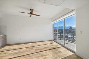 Empty room with hardwood / wood-style flooring, a mountain view, and ceiling fan