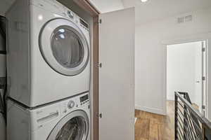 Laundry room featuring light hardwood / wood-style flooring and stacked washer and dryer