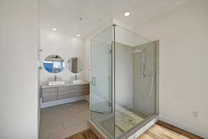 Bathroom with vanity, an enclosed shower, and wood-type flooring