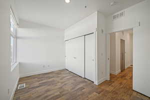 Unfurnished bedroom with dark hardwood / wood-style flooring and a closet