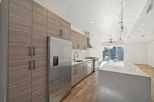 Kitchen with sink, a center island, backsplash, wood-type flooring, and appliances with stainless steel finishes