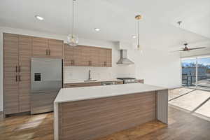 Kitchen featuring sink, wall chimney exhaust hood, stainless steel appliances, dark hardwood / wood-style flooring, and pendant lighting