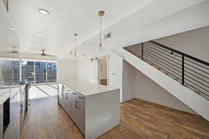 Kitchen with a center island, dark hardwood / wood-style floors, ceiling fan, decorative light fixtures, and a wall of windows