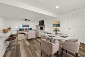 Dining space featuring ceiling fan, a stone fireplace, and wood-type flooring