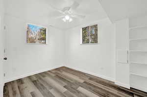 Empty room featuring a wealth of natural light, ceiling fan, and wood-type flooring